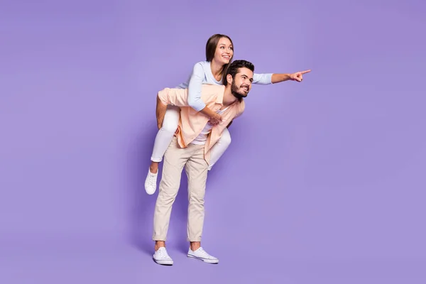 Foto de tamaño completo de la feliz pareja joven hombre a cuestas mujer dedo dedo vacío espacio aislado en el fondo de color púrpura — Foto de Stock