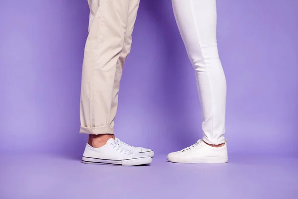 Przycięty profil boczne zdjęcie mężczyzn i kobiet nogi stoją przed sobą nosić białe buty izolowane na fioletowym tle koloru — Zdjęcie stockowe