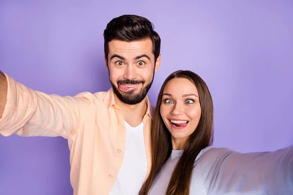 Foto de morena funky cônjuges fazer caras engraçadas tirar câmera selfie blogger casal isolado no fundo cor roxa — Fotografia de Stock