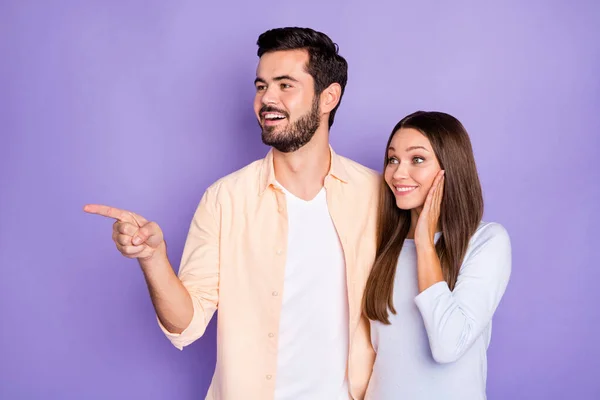 Photo de jeune couple brune regarder vide espace doigt main joue stupéfait isolé sur fond de couleur violette — Photo