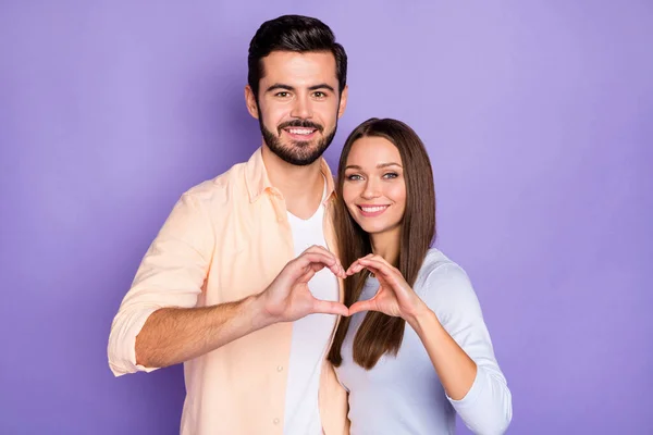 Foto de feliz hombre y mujer cónyuges hacen dedos corazón aniversario forma aislado sobre fondo de color violeta — Foto de Stock