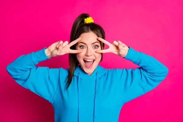 Portret van mooi vrolijk meisje open mond glimlach twee armen vingers tonen v-teken in de buurt van oog geïsoleerd op roze kleur achtergrond — Stockfoto