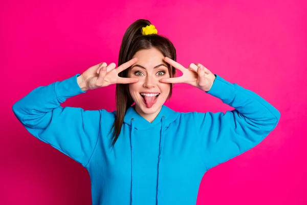 Foto de pessoa bastante positiva dois dedos mãos mostrar v-sinal perto da língua do olho para fora isolado no fundo cor-de-rosa — Fotografia de Stock