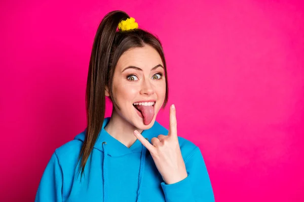 Foto de língua menina bonita positiva para fora dedos mostram símbolo de metal pesado isolado no fundo cor-de-rosa — Fotografia de Stock