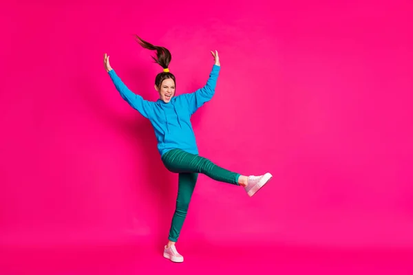 Volledige lengte foto van schattige vrouw gekleed blauwe hoodie dansen rijzende handen staande een been geïsoleerde levendige roze kleur achtergrond — Stockfoto