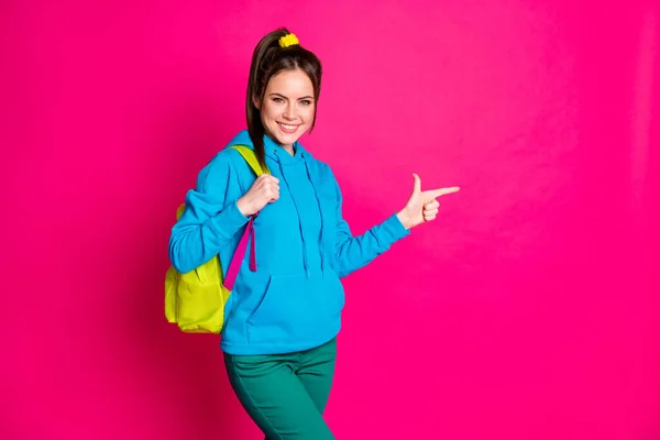 Φωτογραφία από γοητευτικό χαριτωμένο νεαρή κοπέλα φορούν μπλε σακίδιο πουλόβερ δείχνοντας κενό χώρο απομονωμένο φωτεινό ροζ χρώμα φόντο — Φωτογραφία Αρχείου