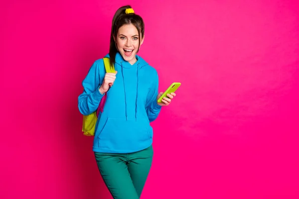 Photo of pretty excited woman dressed blue hoodie backpack holding modern gadget empty space isolated pink color background — Stock Photo, Image