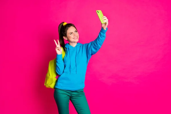 Foto di dolce carino giovane signora indossare blu maglione zaino rendendo selfie dispositivo moderno isolato luminoso colore rosa sfondo — Foto Stock