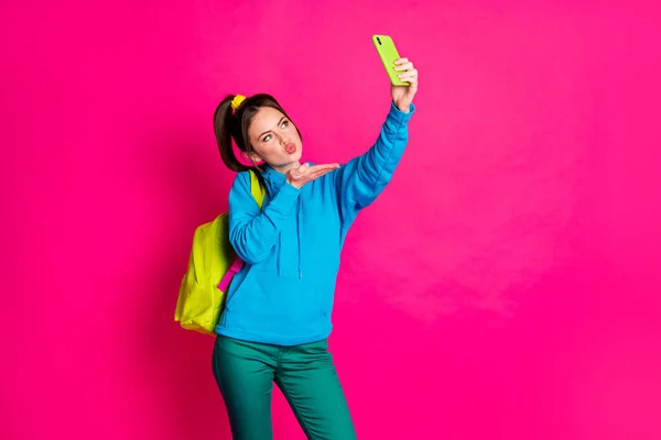 Foto di bella affascinante giovane donna vestita blu con cappuccio zaino auto bacio video moderno gadget isolato colore rosa sfondo — Foto Stock