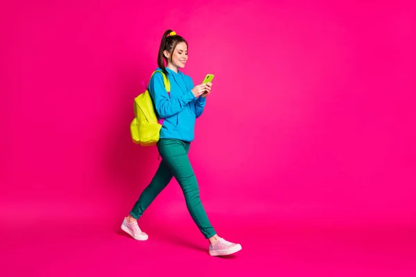 Full längd foto av ganska söt kvinna klädd blå hoodie ryggsäck chatta modern gadget isolerad rosa färg bakgrund — Stockfoto