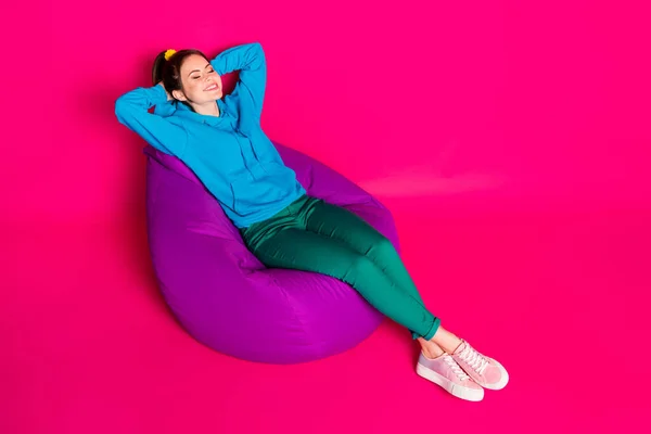 Full length photo of cute woman dressed blue hoodie rest purple bean bag closed eyes arms behind head isolated pink color background — Stock Photo, Image