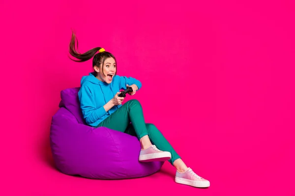 핑크 색 배경에 고립된 안락의자에 앉아 놀고 있는 젊은 펑키웃는 소녀의 전체 크기 사진 — 스톡 사진