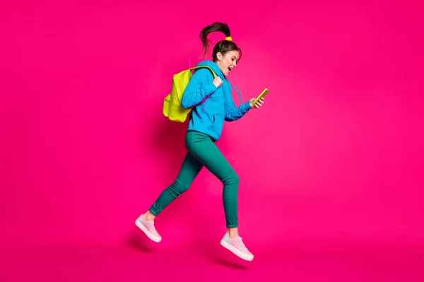 Full längd foto av imponerad rolig ung kvinna klädd blå hoodie ryggsäck skriva modern enhet isolerad rosa färg bakgrund — Stockfoto