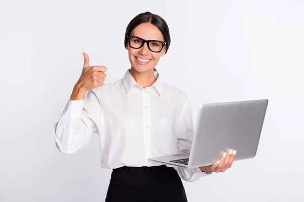 Foto de otimista morena penteado senhora segurar laptop mostrar polegar até desgaste óculos camisa isolada no fundo de cor cinza — Fotografia de Stock