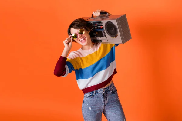 Foto de la señora despreocupada positiva mantenga la caja de la pluma en el hombro toque sunglass aislado en el fondo de color naranja —  Fotos de Stock