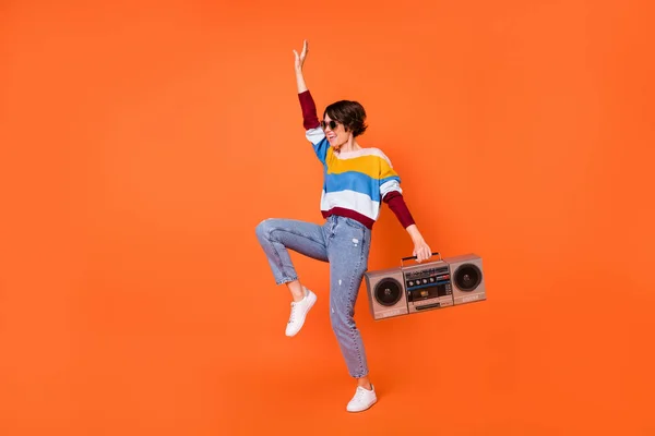 Full length portret van vrolijke koele meisje arm holding recorder genieten dans geïsoleerd op oranje kleur achtergrond — Stockfoto
