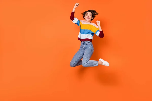 Foto de comprimento total de punhos menina encantada para cima comemorar salto alto isolado no fundo cor de laranja — Fotografia de Stock