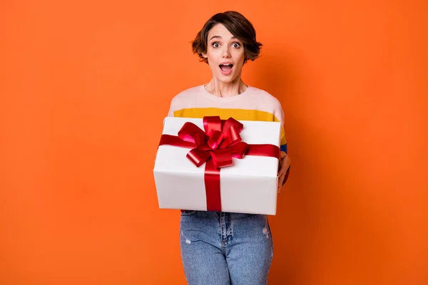 Retrato de brazos de señora bonita impresionada sosteniendo caja de regalo boca abierta mirada cámara aislada sobre fondo de color naranja —  Fotos de Stock