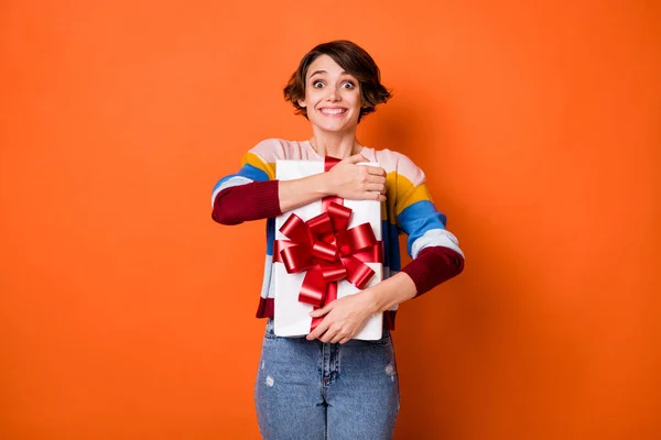 Retrato de atraente surpreendido menina alegre abraçando dom venda desconto isolado sobre fundo de cor laranja brilhante — Fotografia de Stock