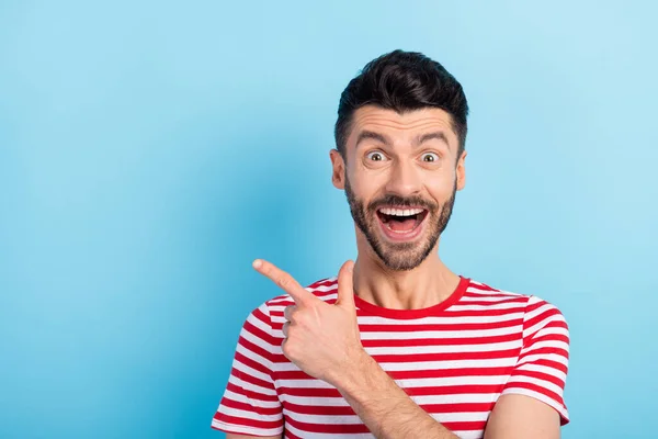 Foto von erstaunt schockiert junger Mann zeigt Zeigefinger leeren Raum Verkauf isoliert auf pastellblauem Hintergrund — Stockfoto