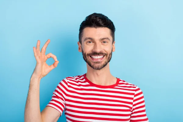 Foto von aufmerksamen netten jungen Mann gekleidet gestreiften T-Shirt zeigt V-Zeichen lächelnd isoliert blaue Farbe Hintergrund — Stockfoto