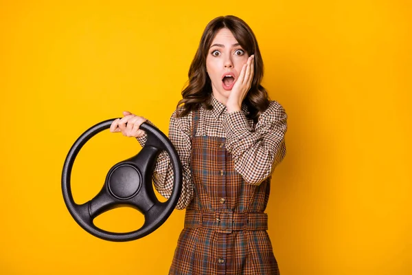 Foto retrato de menina segurando volante tocando bochecha com medo de montar um carro isolado no fundo de cor amarelo vívido — Fotografia de Stock