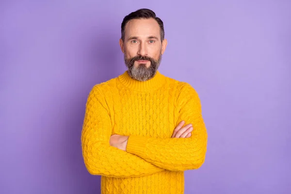 Photo of self-assured bearded man crossed hands look camera wear yellow sweater isolated purple background