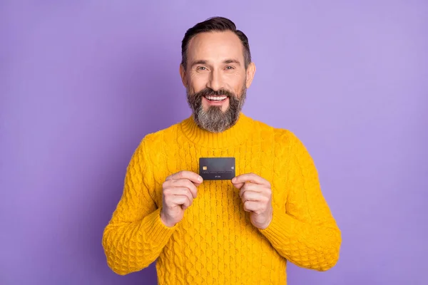 Portret van tevreden man armen houden debetkaart tand glimlach kijken camera geïsoleerd op paarse kleur achtergrond — Stockfoto