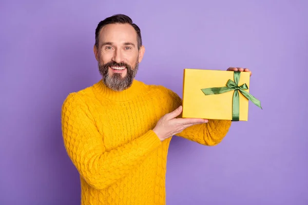 Foto de homem positivo segurar giftbox toothy beaming sorriso desgaste amarelo pulôver isolado violeta fundo — Fotografia de Stock