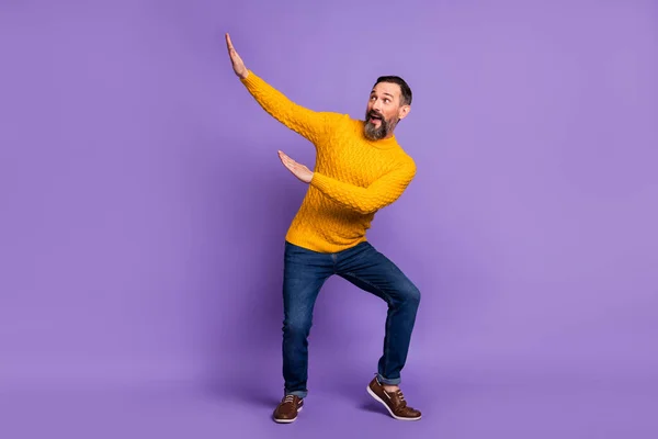 Foto von funky crazy man dance raise hands look empty space wear yellow pullover isoliert violetten Hintergrund — Stockfoto