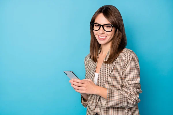 Profil foto av optimistisk brunett dam titta telefon bära glasögon brun jacka isolerad på levande blå bakgrund — Stockfoto