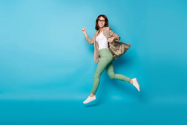Plná délka fotografie portrét veselá dívka běží skákání nahoru izolované na živé modré barevné pozadí — Stock fotografie