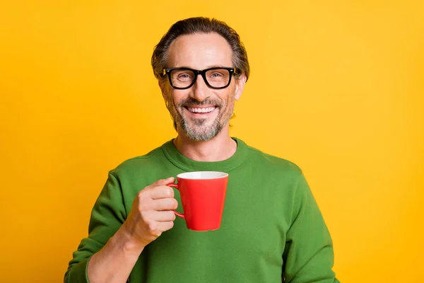 Foto de hombre sostener taza diente radiante sonrisa usar gafas suéter verde aislado color amarillo fondo — Foto de Stock