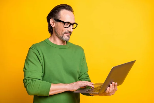 Photo of smart guy hold laptop munka megjelenés képernyő kopás szemüveg zöld pulóver izolált sárga szín háttér — Stock Fotó