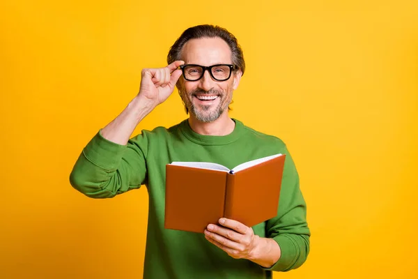 Foto de chico mantenga el aspecto del libro de texto cámara sonrisa brillante desgaste jersey verde aislado color amarillo fondo — Foto de Stock