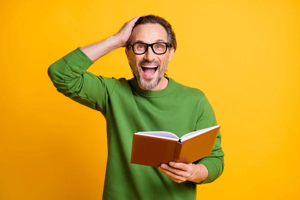 Photo of man hold book look camera open mouth arm head wear glasses zielony sweter odizolowany żółty kolor tło — Zdjęcie stockowe