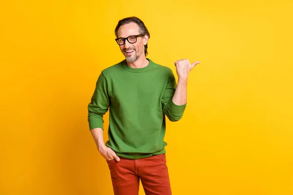 Foto de tipo divertido indican dedo vacío espacio gafas suéter verde aislado color amarillo fondo —  Fotos de Stock