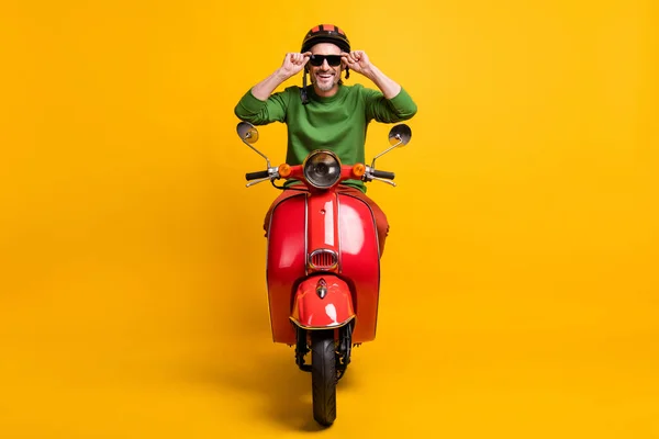 Zdjęcie wesoły facet jazdy rower nosić kask sunglass zielony sweter odizolowany żółty kolor tło — Zdjęcie stockowe