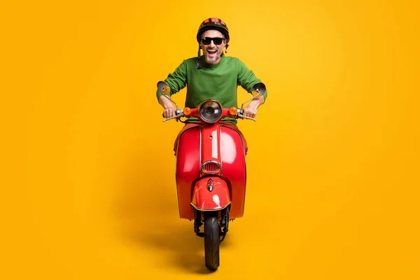 Foto von Crazy Man Ride Zyklus offenen Mund tragen Helm Sonnenbrille grünen Pullover isoliert gelbe Farbe Hintergrund — Stockfoto