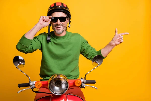 Foto pria berjenggot naik skuter jari langsung kosong ruang memakai helm spesifikasi hijau sweater terisolasi warna kuning latar belakang — Stok Foto