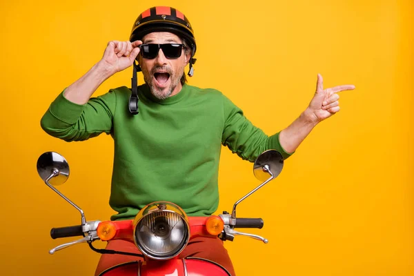 Foto pria dewasa mengendarai sepeda motor menunjukkan jari kosong ruang iklan menyarankan pilihan terisolasi dari latar belakang warna kuning — Stok Foto