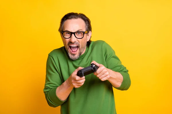 Foto de funky gamer guy hold gamepad play videojuego usar gafas verde jersey aislado color amarillo fondo — Foto de Stock