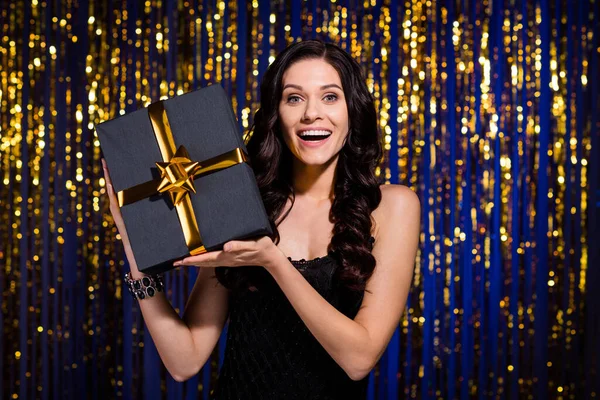 Foto de las manos de la muchacha encantadora asombrada sostiene la cámara de aspecto de caja de regalo aislada en la cortina decorada brillante —  Fotos de Stock