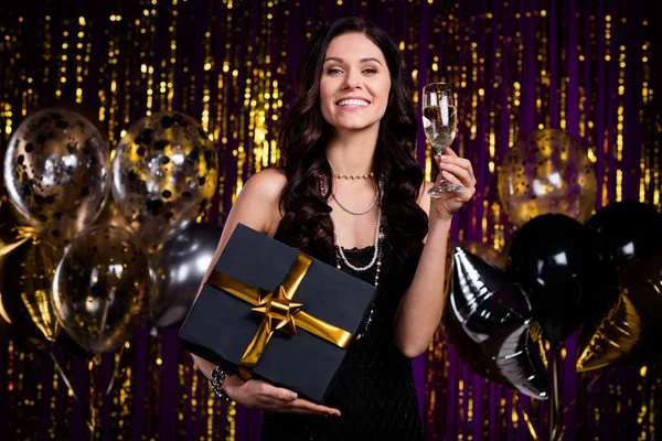 Foto van prachtige blij dame houden giftbox champagne glas tand glimlach geïsoleerd op versierd nieuwjaar muur — Stockfoto