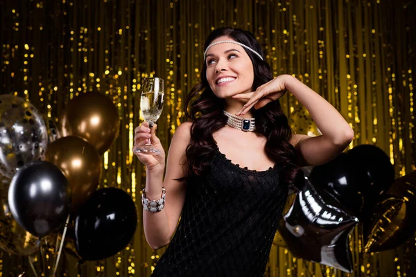 Foto van zoete glanzende jonge dame dragen glamour jurk hoofd band op zoek naar lege ruimte drinken cocktail geïsoleerde glitter achtergrond — Stockfoto