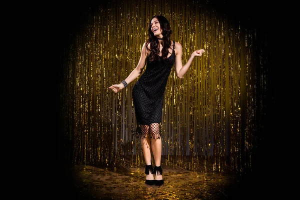 Фотография коричневого оптимиста в черном платье на темно-золотом фоне в свете сцены — стоковое фото