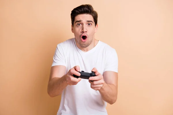 Bild av imponerad ung kille gamer öppen mun skriker glada spel isolerad på beige färg bakgrund — Stockfoto