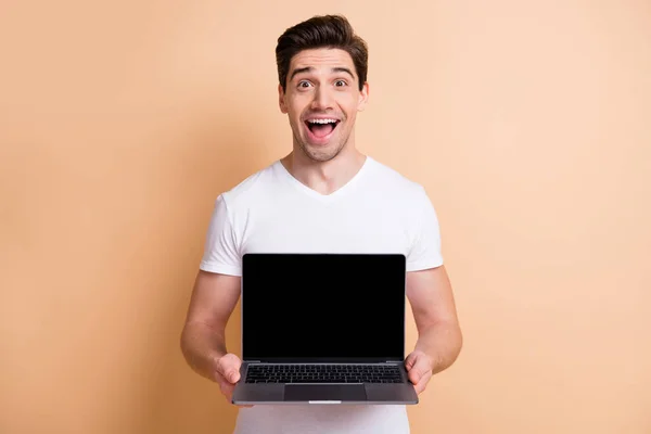 Φωτογραφία του εντυπωσιακού όμορφος πρόσωπο ανοιχτό στόμα κρατήσει netbook δείχνει οθόνη απομονωμένη σε μπεζ φόντο χρώμα — Φωτογραφία Αρχείου