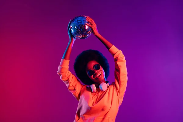 Портрет привлекательный положительный темная кожа девушка зубастый улыбка держать диско мяч над головой изолированы на ярком фоне — стоковое фото