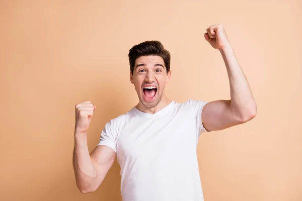 Foto van zegevierende gelukkig guy raise vuisten bereiken doel schreeuwen ja geïsoleerd op beige kleur achtergrond — Stockfoto